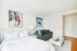 een witte slaapkamer met een bed en een bank bij Spectacular Studio in Manhattan in New York