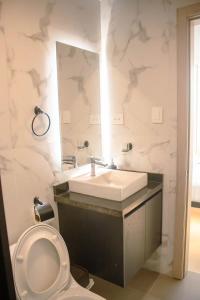 W łazience znajduje się umywalka, toaleta i lustro. w obiekcie Hotel Amazonas Suite , habitación sencilla w Nueva Loja