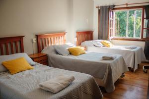 a room with three beds and a window at Hotel Pintó Terraza in Esquel