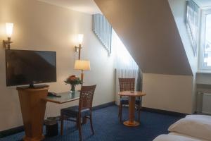 Habitación de hotel con cama y escritorio con TV. en Hotel Daniel en Múnich