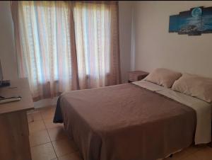 ein Schlafzimmer mit einem Bett und einem Fenster mit Vorhängen in der Unterkunft Departamentos Vila in Mina Clavero