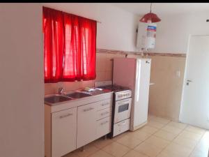 eine Küche mit einer Spüle, einem Herd und einem Kühlschrank in der Unterkunft Departamentos Vila in Mina Clavero