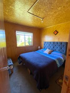 een slaapkamer met een blauw bed en een raam bij Cabañas Los Queltehues in Chacao Viejo
