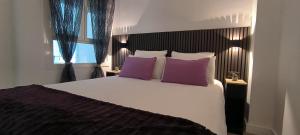 a bedroom with a large white bed with purple pillows at Denia Beach Apartament Jardín privado y piscina in El Verger