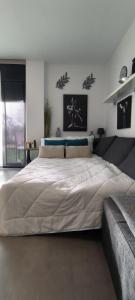 Una gran cama blanca en un dormitorio con un sofá. en Denia Beach Apartment Jardín privado y piscina, en El Verger