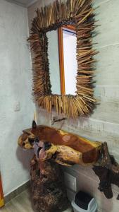 a mirror on the wall of a bathroom with a tree stump at Finca Nuevo Monarca in Pereira