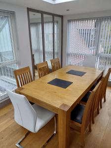 a wooden dining room table with chairs and windows at Silvercopse House in Kingston Bagpuze