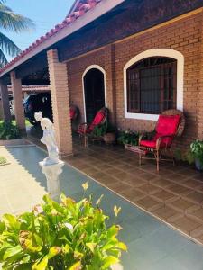 a house with two chairs and a statue on a patio at Maravilhosa Casa a 20 Metros da PRAIA in Caraguatatuba