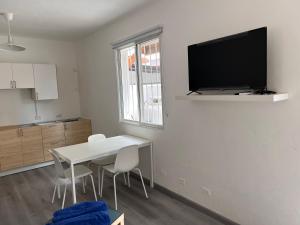 uma sala de estar com uma mesa branca e uma televisão na parede em EMY HOUSE em La Laguna