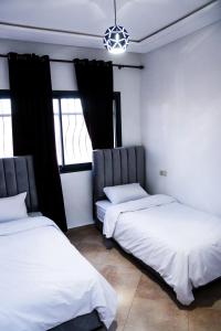 2 camas en una habitación con ventanas en Baya view surfside, en Aourir