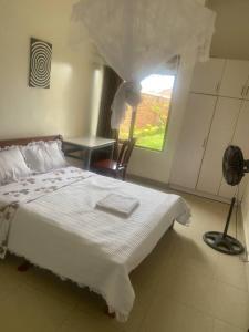 1 dormitorio con cama, escritorio y ventana en Adriel homes and tours en Kigali