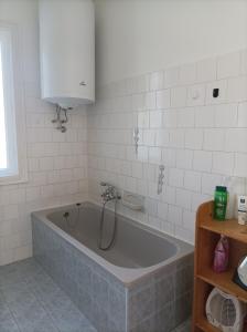 een bad in een wit betegelde badkamer bij Róza Vendégház in Kiskunhalas
