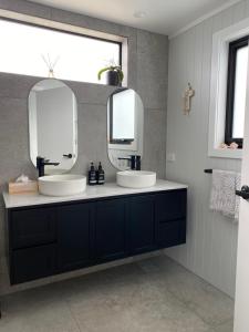 a bathroom with two sinks and two mirrors at The Beach House @ Primrose Sands in Primrose Sands