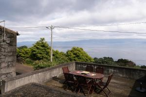 una mesa y sillas en un balcón con vistas al océano en Villa Mistério en São Roque do Pico