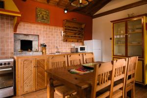 cocina con mesa de madera, fregadero y fogones en Villa Mistério en São Roque do Pico