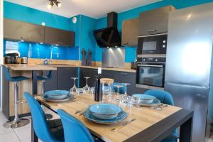 - une cuisine avec une table en bois et des murs bleus dans l'établissement Le Beluga XL - Appartement proche Airbus, à Colomiers