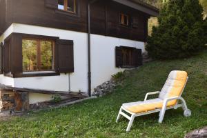 una silla sentada en el césped frente a una casa en Chalet familial pour l'été, en Troistorrents