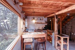 uma cozinha com uma mesa e bancos num quarto em Cabaña Dakota, Ushuaia em Ushuaia