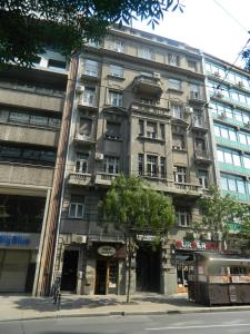 Un palazzo alto in una strada di città con un autobus di Authentic Belgrade Centre Hostel - Only Private Rooms, Paid Parking on-site, Mandatory Reservation a Belgrado