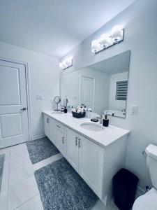 a white bathroom with a sink and a mirror at Brand New! Modern Luxury Retreat! in Barrie