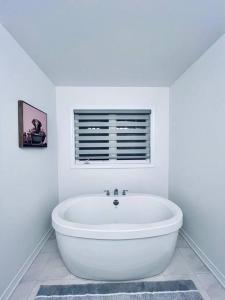 baño blanco con bañera y ventana en Brand New! Modern Luxury Retreat! en Barrie