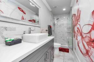 La salle de bains est pourvue d'un lavabo et d'une douche avec graffitis rouges. dans l'établissement Prolific Red Luxe: Private Deck + Stylish Living, à Houston 41 autres photos