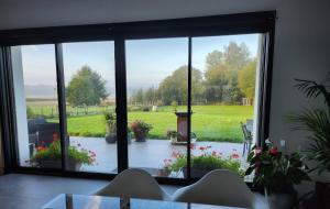 a view of a garden through a large window at Les ateliers in Nivelle +1 photo