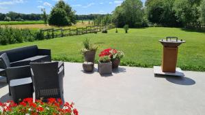a patio with a bench and a bird feeder and flowers at Les ateliers in Nivelle