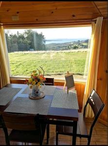a dining room table with a view of a field at Domo Vientos del Sur in Ancud