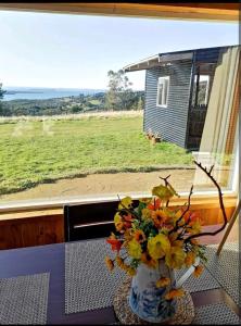 a vase of flowers on a table in front of a window at Domo Vientos del Sur in Ancud