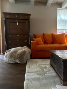 a living room with an orange couch and a dresser at City House Grande Madame Agaath in Leeuwarden