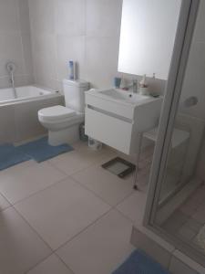 a white bathroom with a toilet and a sink at Leisure apartment in Ballito