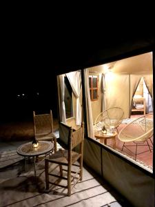 a room with two chairs and a table and two tables at Palmyra Luxury Camp in Merzouga