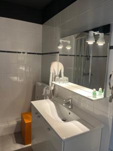 Baño blanco con lavabo y espejo en Le Téméraire Hôtel en Charolles