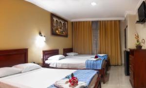 una camera d'albergo con tre letti e una televisione di Airport Hotel Guayaquil a Guayaquil