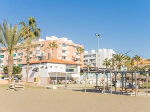 un gruppo di edifici con palme e parco giochi di Completo Estudio con Piscina en la Costa a Cala del Moral