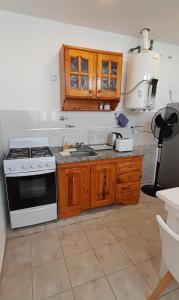 cocina con fogones, fregadero y armarios de madera en Belgrano 238 en Capilla del Monte
