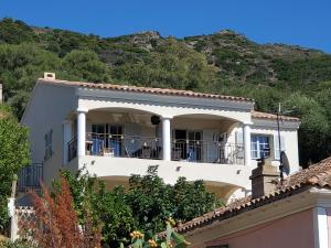 una casa bianca con alberi e montagne sullo sfondo di VILLA U TEMPIU CORSU a Patrimonio