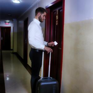 a man standing with a suitcase in a hallway at Airport Hotel Guayaquil in Guayaquil