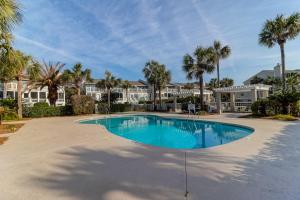 een zwembad met palmbomen en huizen bij 22 Beach Club Villa in Isle of Palms