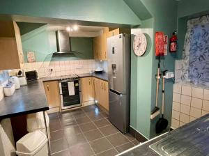 a kitchen with a stainless steel refrigerator and green walls at Gorwel, Spacious 3 Bedroom Cottage near the Beach in Llanarth