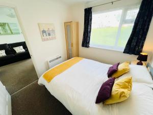 ein Schlafzimmer mit einem großen Bett mit gelben und violetten Kissen in der Unterkunft 2 Bedroom Chalet SB113, Sandown Bay, Isle of Wight in Brading
