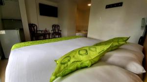 Una cama blanca con una manta verde. en Hotel Anzea, en Anserma
