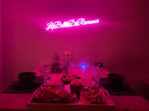 a pink room with a table with a pink neon sign at La Bulle de Romance - Love Room in Tigy +4 photos