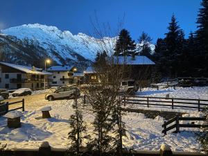 ein schneebedecktes Dorf mit einem Zaun und einem Berg in der Unterkunft Appartamento Valtournenche in Valtournenche