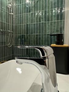 W łazience znajduje się biała umywalka i wyłożona zielonymi kafelkami ściana. w obiekcie Bali suites - Basel / Dreilander w mieście Saint-Louis