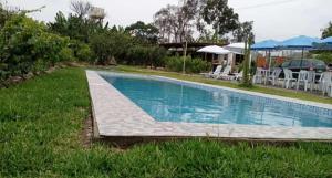 einen Pool im Garten mit Stühlen und Sonnenschirmen in der Unterkunft Peñaflor in Miraflores