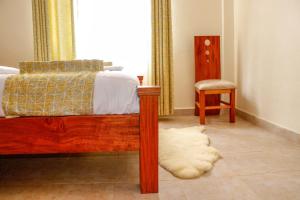 a bedroom with a bed and a chair next to a window at J&J luxury homes in Kericho