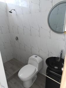 uma casa de banho branca com um WC e um espelho. em Departamentos de playa em Cerro Azul