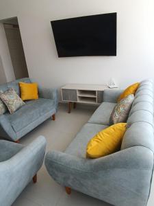uma sala de estar com 2 sofás e uma televisão de ecrã plano em Departamentos de playa em Cerro Azul